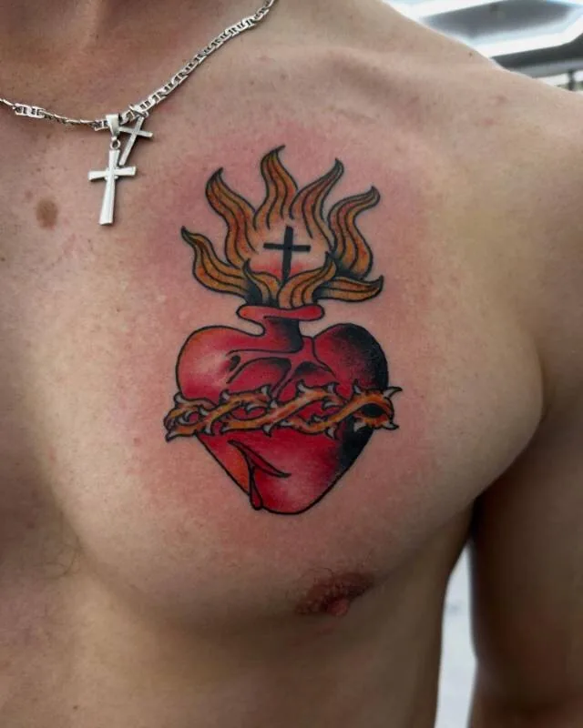 American Traditional sacred-heart chest tattoo crowned with a flame and cross and bound with a crown of thorns, by Julian (xwildxlovex) at Ohana Tattoo, Waikiki, Hawaii.